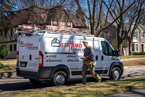 a stafford home service technician is walking towards the camera while smiling, holding tools in his hand.